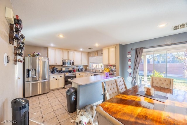 kitchen featuring light tile patterned floors, sink, kitchen peninsula, and appliances with stainless steel finishes