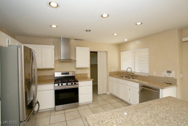 kitchen with light tile patterned flooring, appliances with stainless steel finishes, white cabinetry, sink, and wall chimney exhaust hood