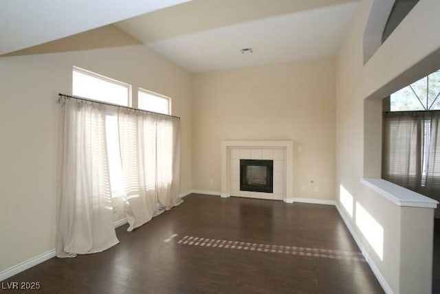 unfurnished living room with lofted ceiling, dark hardwood / wood-style flooring, and a tiled fireplace