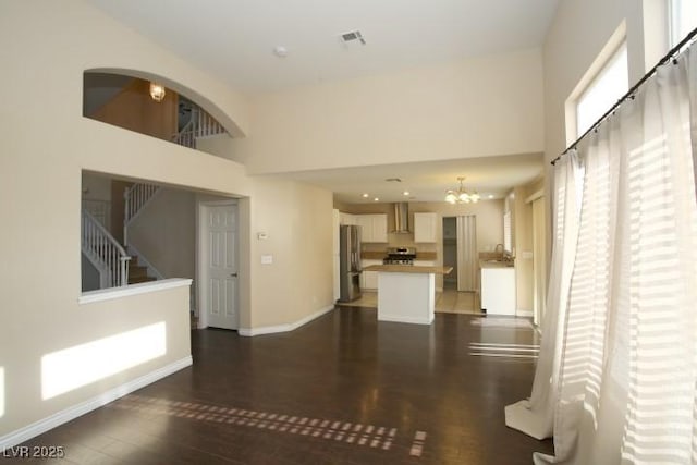 unfurnished living room with a high ceiling, a notable chandelier, and dark hardwood / wood-style flooring