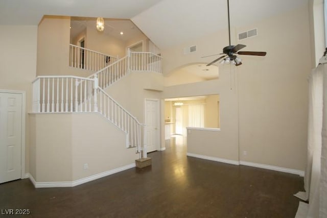 unfurnished living room with ceiling fan, dark hardwood / wood-style floors, and high vaulted ceiling