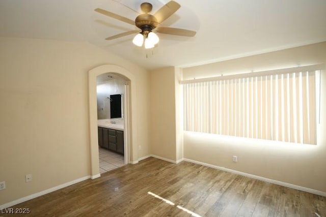 spare room featuring lofted ceiling, ceiling fan, and light wood-type flooring