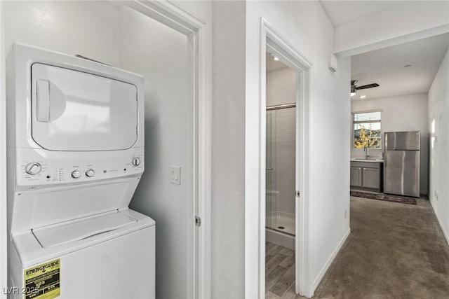 laundry room with stacked washer and dryer, dark carpet, sink, and ceiling fan