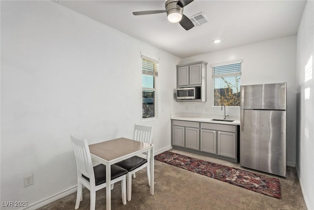 kitchen featuring stainless steel appliances, sink, gray cabinetry, and dark carpet