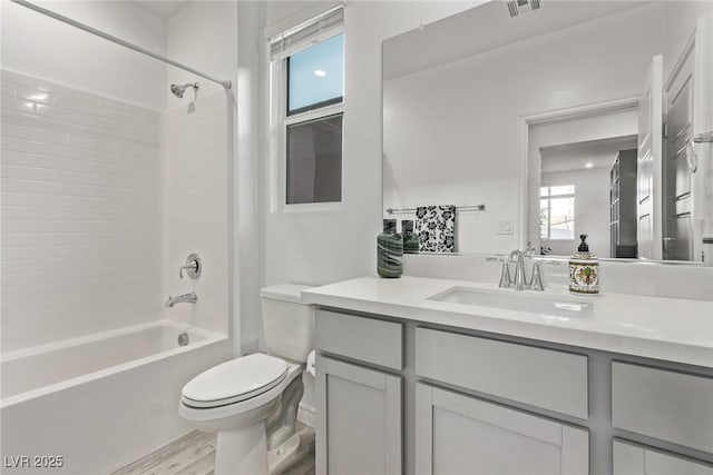 full bathroom with tiled shower / bath, vanity, toilet, and wood-type flooring