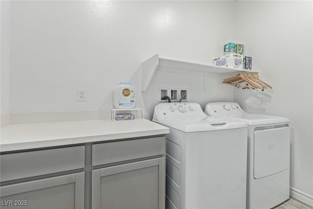 clothes washing area featuring cabinets and washing machine and clothes dryer