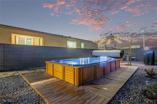 deck at dusk featuring area for grilling and a hot tub