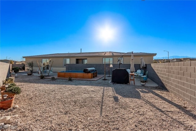 rear view of house with a jacuzzi and a patio area