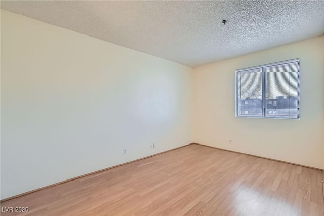 spare room featuring a textured ceiling and light wood-type flooring