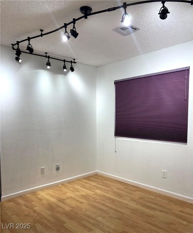 spare room featuring wood-type flooring and a textured ceiling