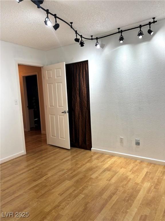 unfurnished room featuring a textured ceiling and light hardwood / wood-style floors