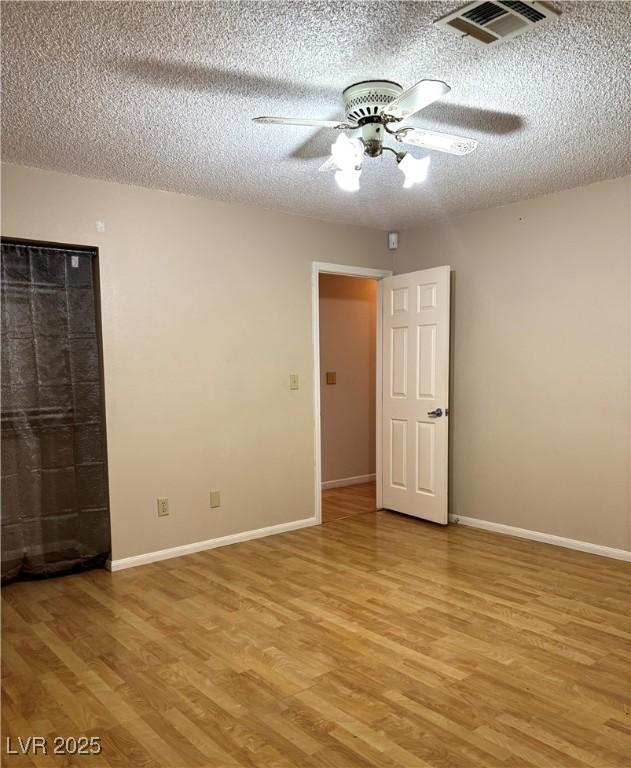 empty room featuring ceiling fan, light hardwood / wood-style floors, and a textured ceiling