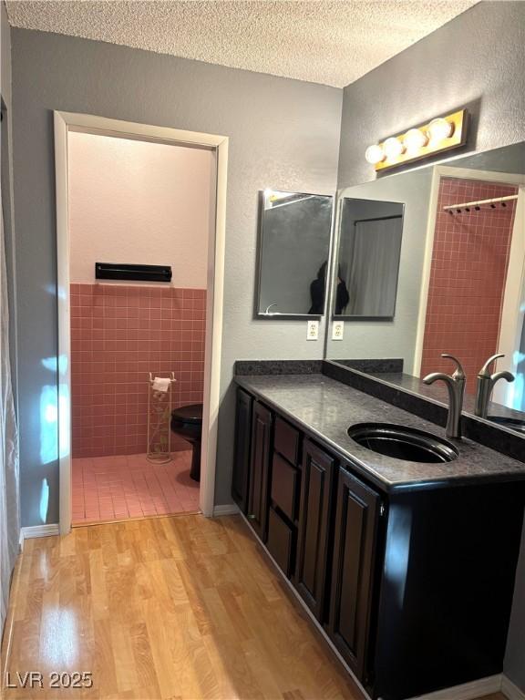 bathroom featuring vanity, wood-type flooring, a textured ceiling, toilet, and walk in shower