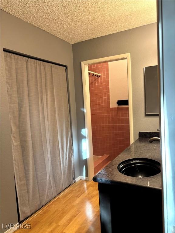 bathroom featuring vanity, hardwood / wood-style floors, a textured ceiling, and walk in shower