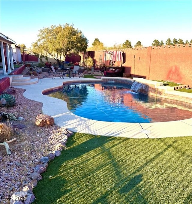 view of swimming pool with pool water feature, a lawn, and a patio area