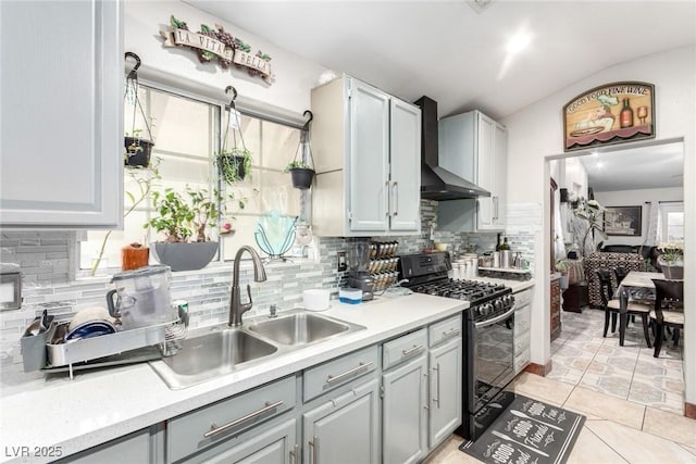 kitchen featuring sink, black gas stove, gray cabinetry, decorative backsplash, and wall chimney exhaust hood