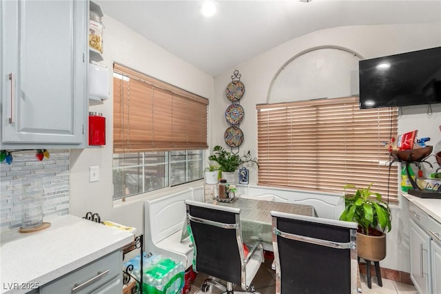 interior space with tasteful backsplash, lofted ceiling, light tile patterned floors, and gray cabinetry