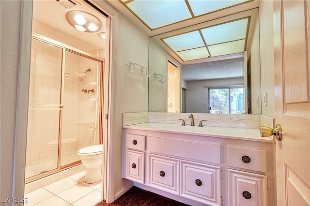 bathroom featuring toilet, vanity, tile patterned floors, and a shower with shower door