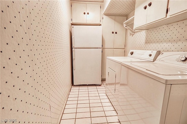 laundry room featuring cabinets, light tile patterned floors, and independent washer and dryer