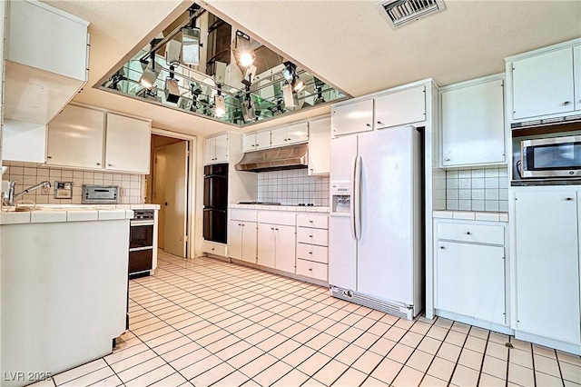 kitchen with white cabinetry, backsplash, tile counters, and black appliances