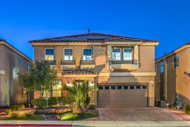 mediterranean / spanish house featuring central AC, a balcony, a garage, and solar panels