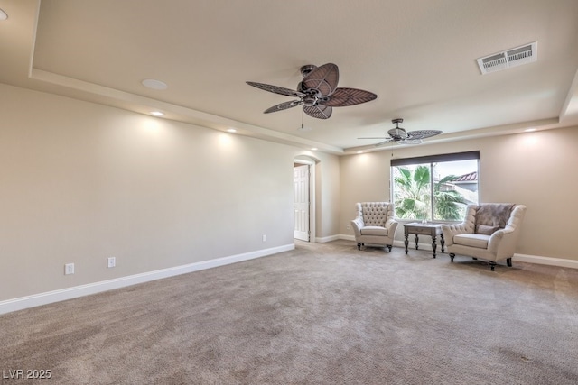 unfurnished room with a raised ceiling, carpet floors, and ceiling fan