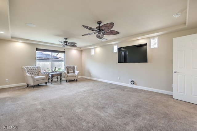 unfurnished room with a raised ceiling, carpet, and ceiling fan