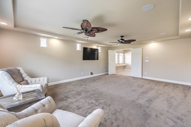 unfurnished living room with carpet floors, a wealth of natural light, ceiling fan, and a tray ceiling