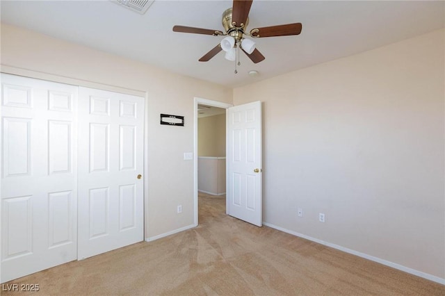 unfurnished bedroom featuring light carpet, ceiling fan, and a closet