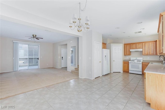 kitchen featuring sink, light brown cabinets, hanging light fixtures, light carpet, and white appliances