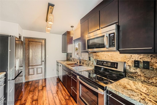 kitchen featuring stainless steel appliances, tasteful backsplash, light stone countertops, and pendant lighting