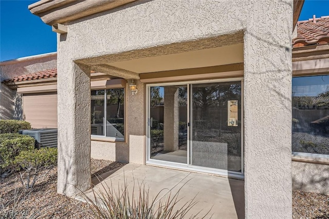 property entrance featuring cooling unit and a patio area