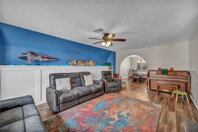 living room featuring hardwood / wood-style floors, ceiling fan with notable chandelier, and a textured ceiling