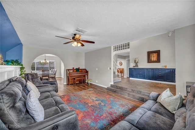 living room featuring hardwood / wood-style flooring, ceiling fan with notable chandelier, and a textured ceiling