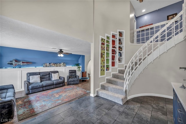 stairway with a textured ceiling, ceiling fan, and a high ceiling