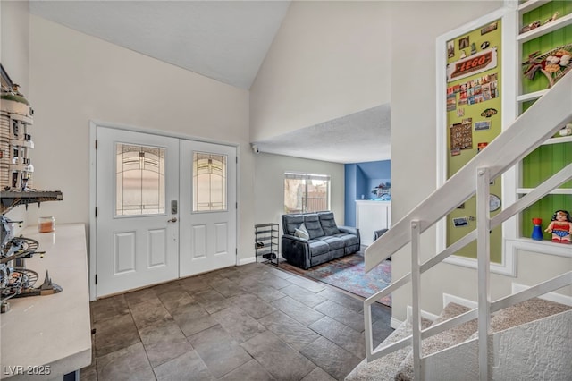 foyer entrance featuring high vaulted ceiling and french doors