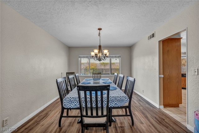 dining space featuring an inviting chandelier, hardwood / wood-style floors, and a textured ceiling