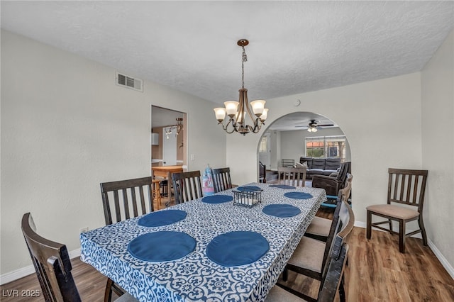 dining room featuring ceiling fan with notable chandelier, hardwood / wood-style floors, and a textured ceiling