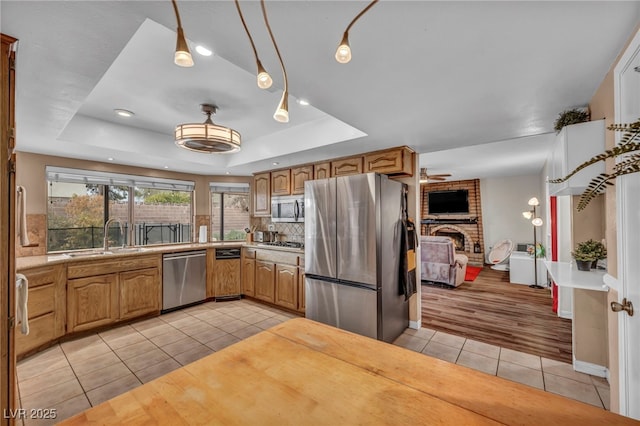 kitchen featuring sink, light tile patterned flooring, a raised ceiling, and appliances with stainless steel finishes