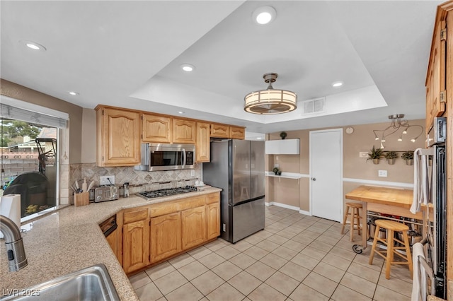 kitchen with tasteful backsplash, sink, a raised ceiling, and appliances with stainless steel finishes