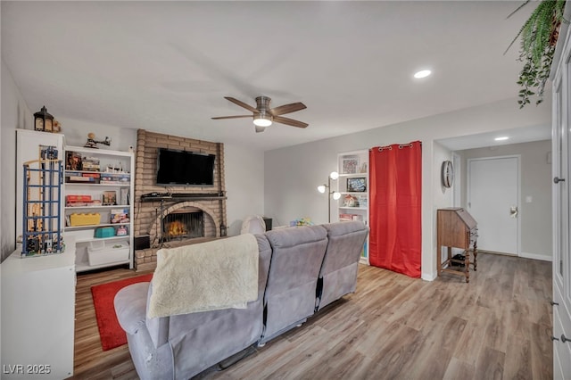 living room featuring a brick fireplace, light hardwood / wood-style flooring, and ceiling fan