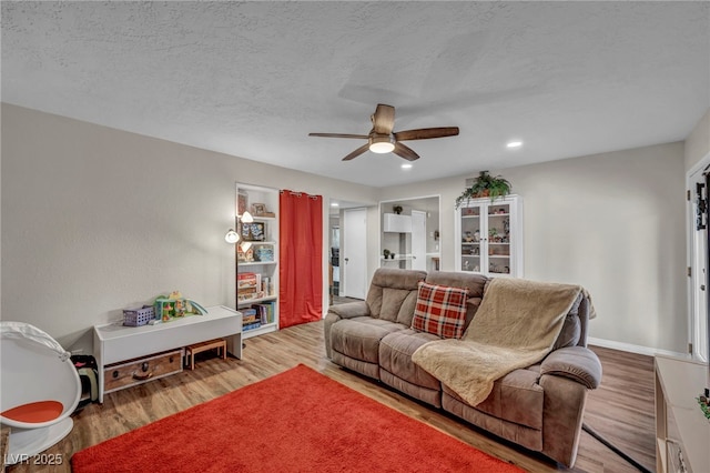 living room with hardwood / wood-style floors, a textured ceiling, and ceiling fan