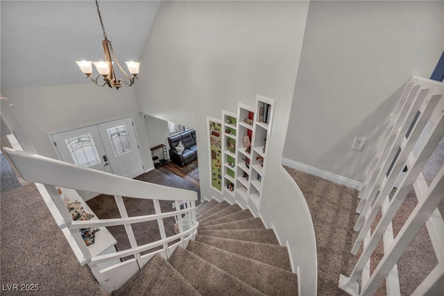 stairs featuring a high ceiling, carpet, an inviting chandelier, and french doors