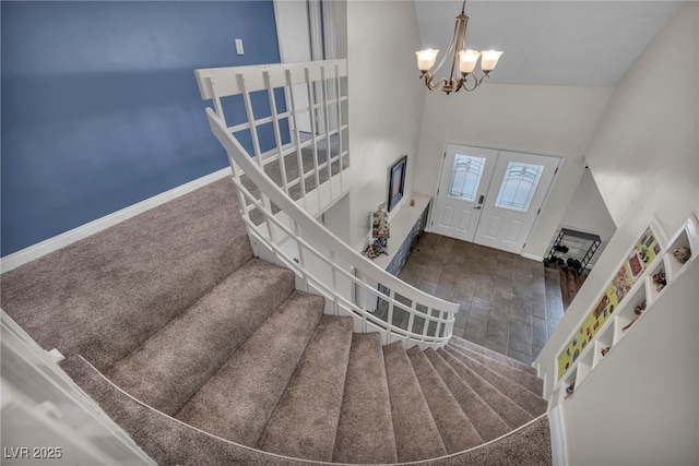 foyer with a notable chandelier, dark carpet, french doors, and a high ceiling