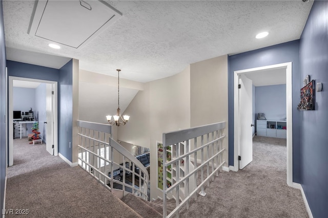 hallway with an inviting chandelier, lofted ceiling, carpet floors, and a textured ceiling