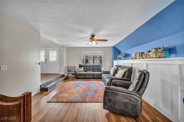 living room featuring wood-type flooring, lofted ceiling, ceiling fan, and a textured ceiling