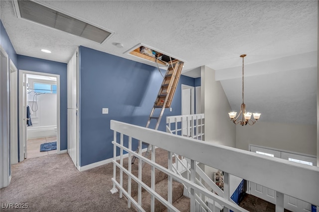 corridor featuring carpet floors, a textured ceiling, and a notable chandelier