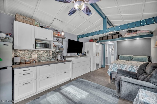 bedroom featuring lofted ceiling, stainless steel fridge, and sink