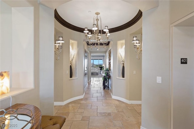 corridor with a notable chandelier and crown molding