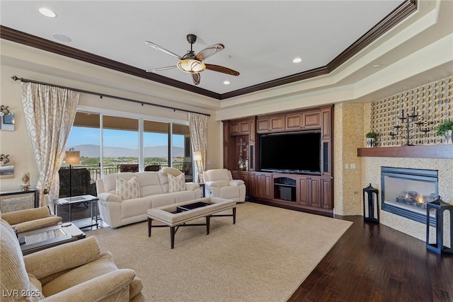 living room with ceiling fan, ornamental molding, a tray ceiling, and dark hardwood / wood-style flooring